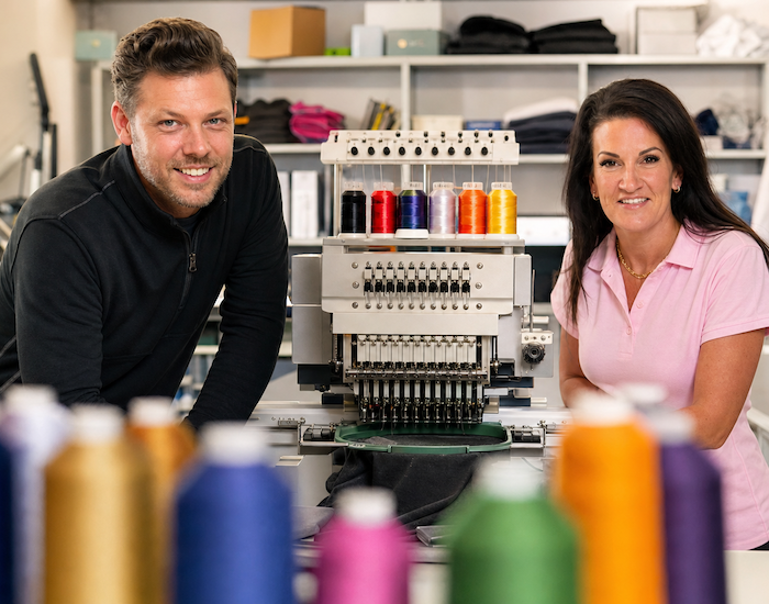 Neil and Jodie, owners of Rag Box Clothing, at their embroidery machine in Basingstoke